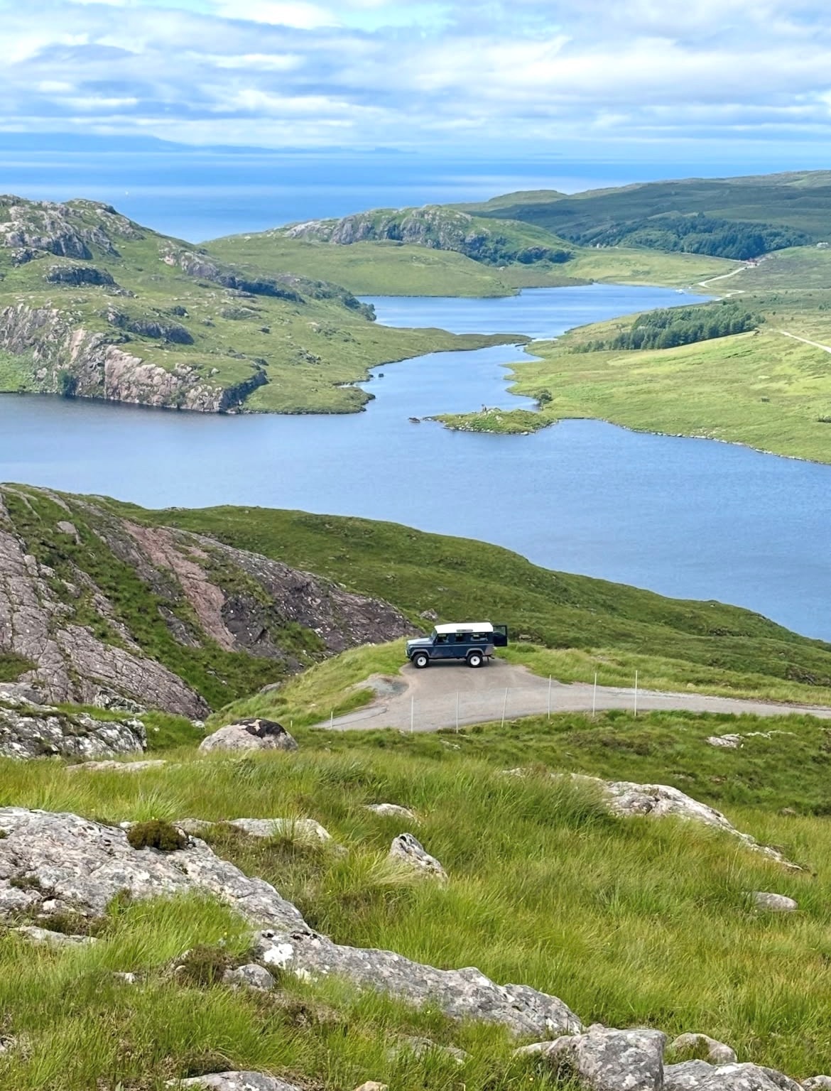 Bluebell the Land Rover Defender parked on a highland road overlooking a Scottish loch